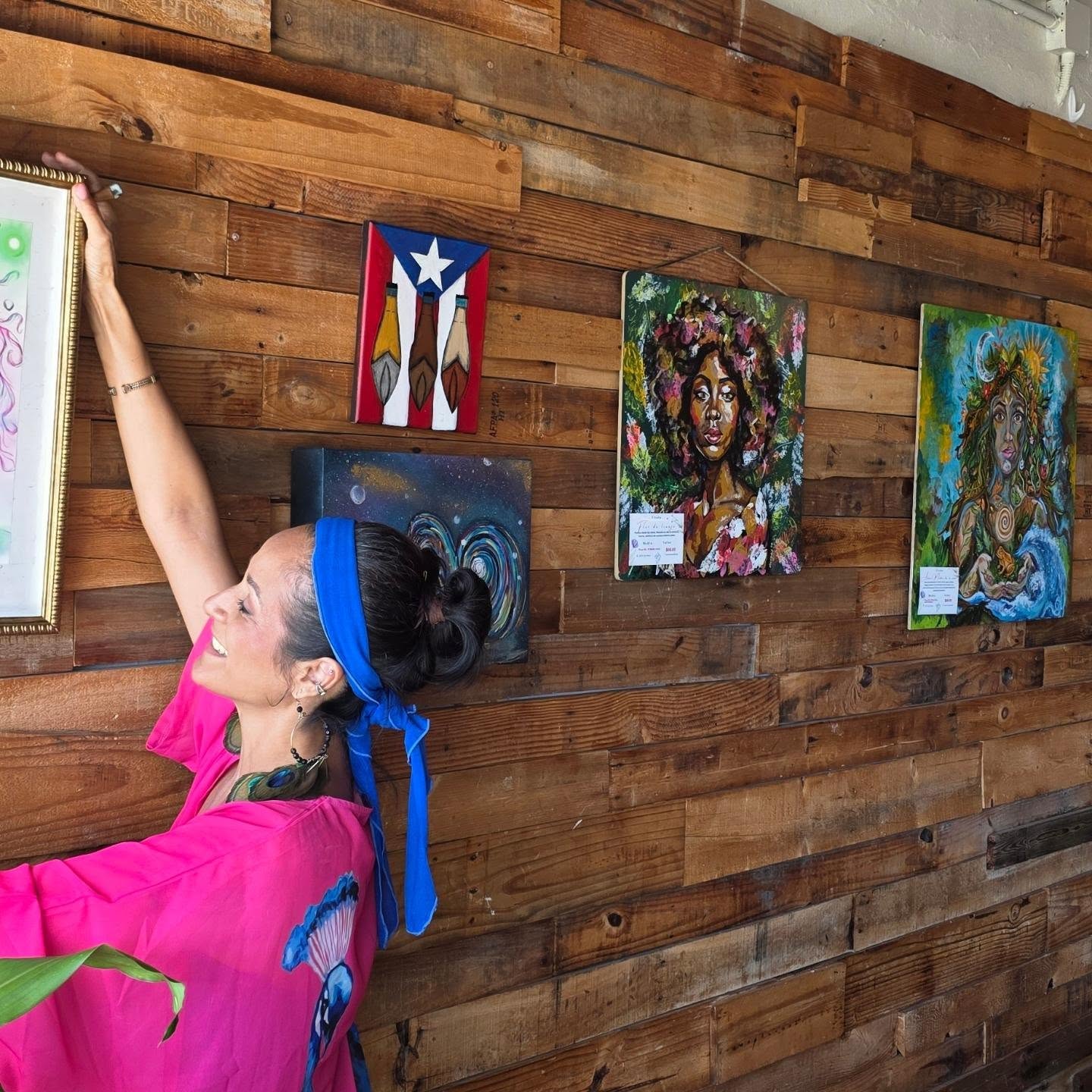 Artista junto a una pared de madera con obras expuestas en Galería Obrigada